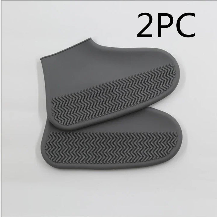 Pair of gray waterproof shoe covers with textured anti-slip soles on white background