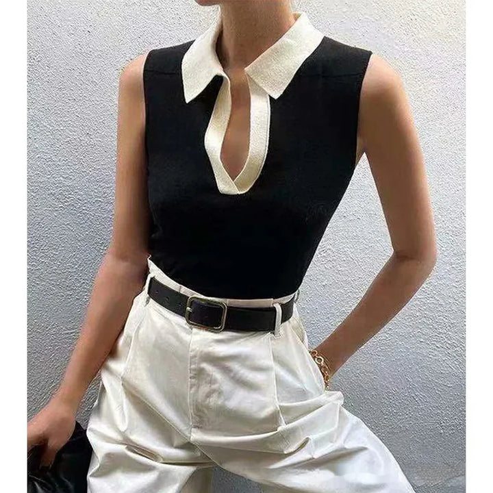Sleeveless black top with white collar and V-neck paired with high-waisted white pants and black belt