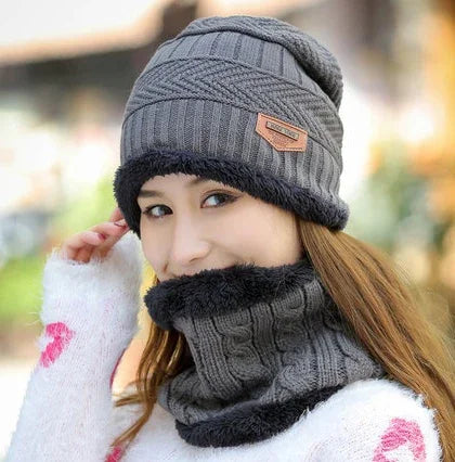 Woman wearing gray knit beanie and matching cable knit neck warmer with black fur trim outdoors