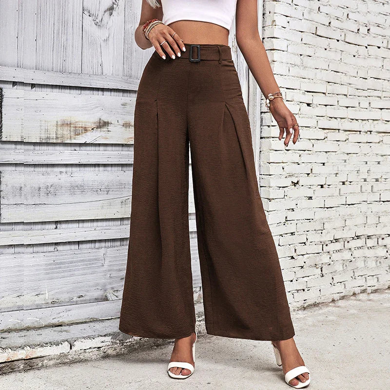 Woman wearing high-waisted wide-leg brown pants with belt detail and white open-toe heels