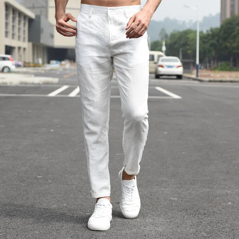 Man wearing slim fit white pants and white sneakers walking on urban street