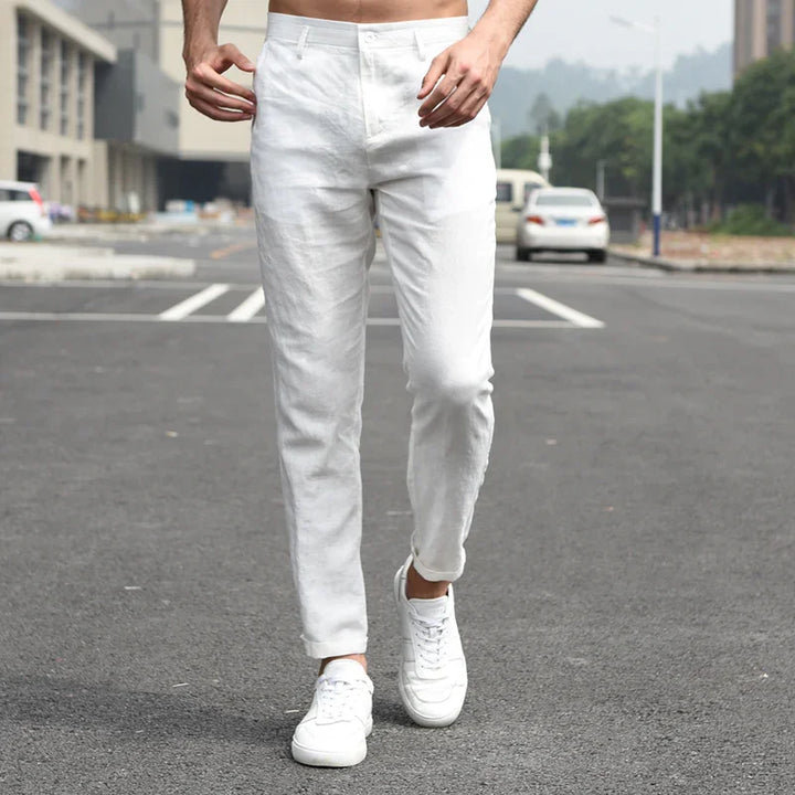 Man wearing slim fit white pants and white sneakers walking on urban street