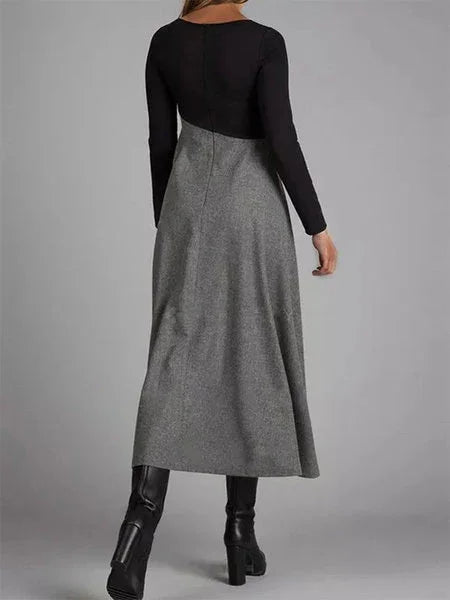 woman wearing a black and gray long-sleeve midi dress with black heeled boots on gray background