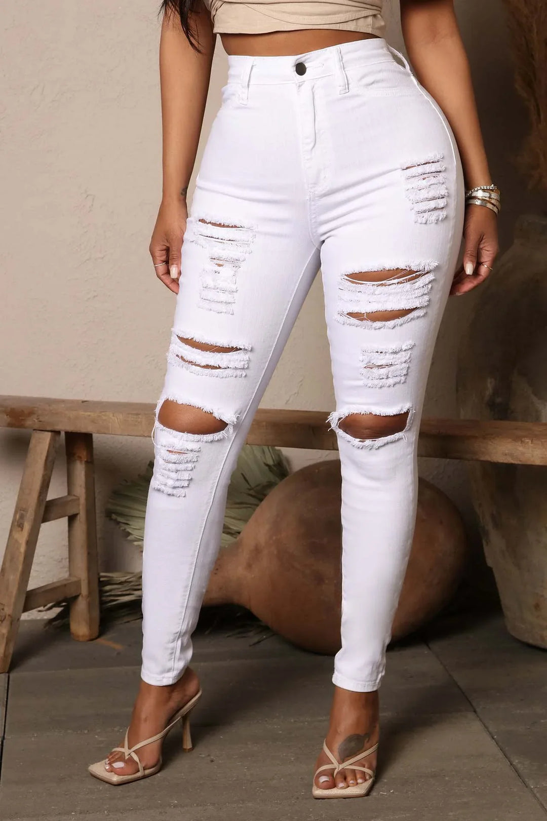 Woman wearing high-waisted white distressed skinny jeans and beige heeled sandals