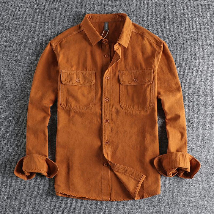 Men's rust brown casual button-up shirt with two chest flap pockets on gray fabric