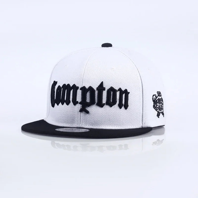 White snapback hat with black brim and bold black 'Compton' embroidery on front