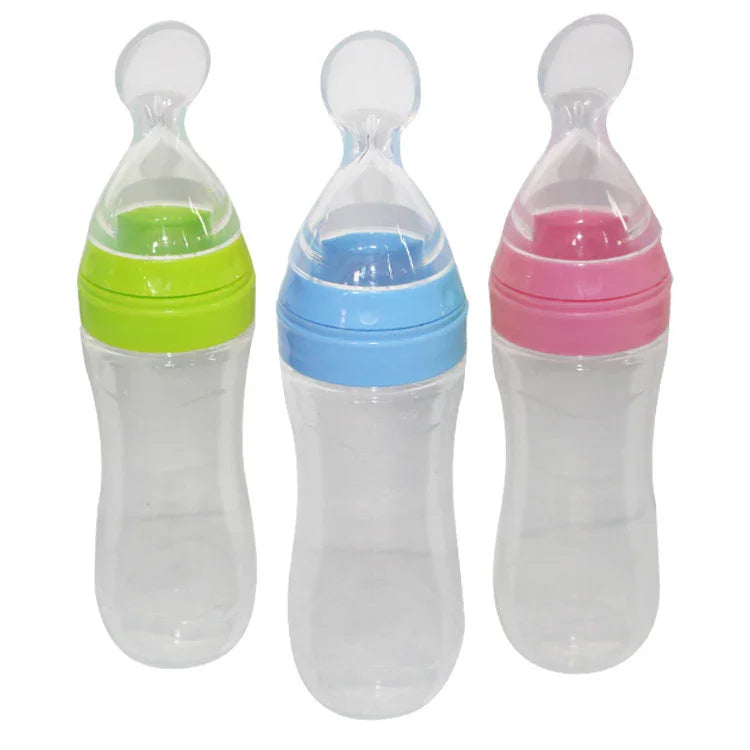 Set of three clear baby feeding bottles with soft silicone spoons in green, blue, and pink colors