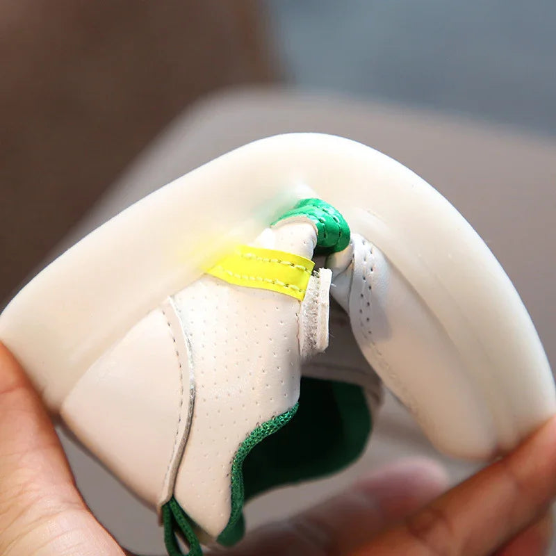 Close-up of a flexible white sneaker with green and yellow accents being folded by hand