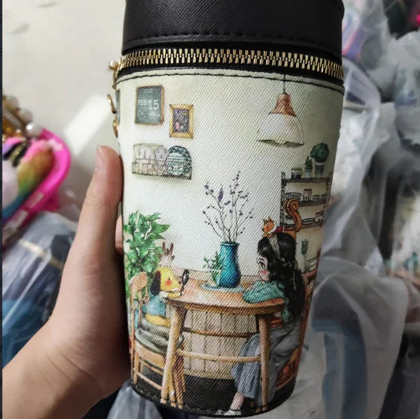 Hand holding a cylindrical bag with a cute illustration of girl and animal sitting at a table in a cozy room