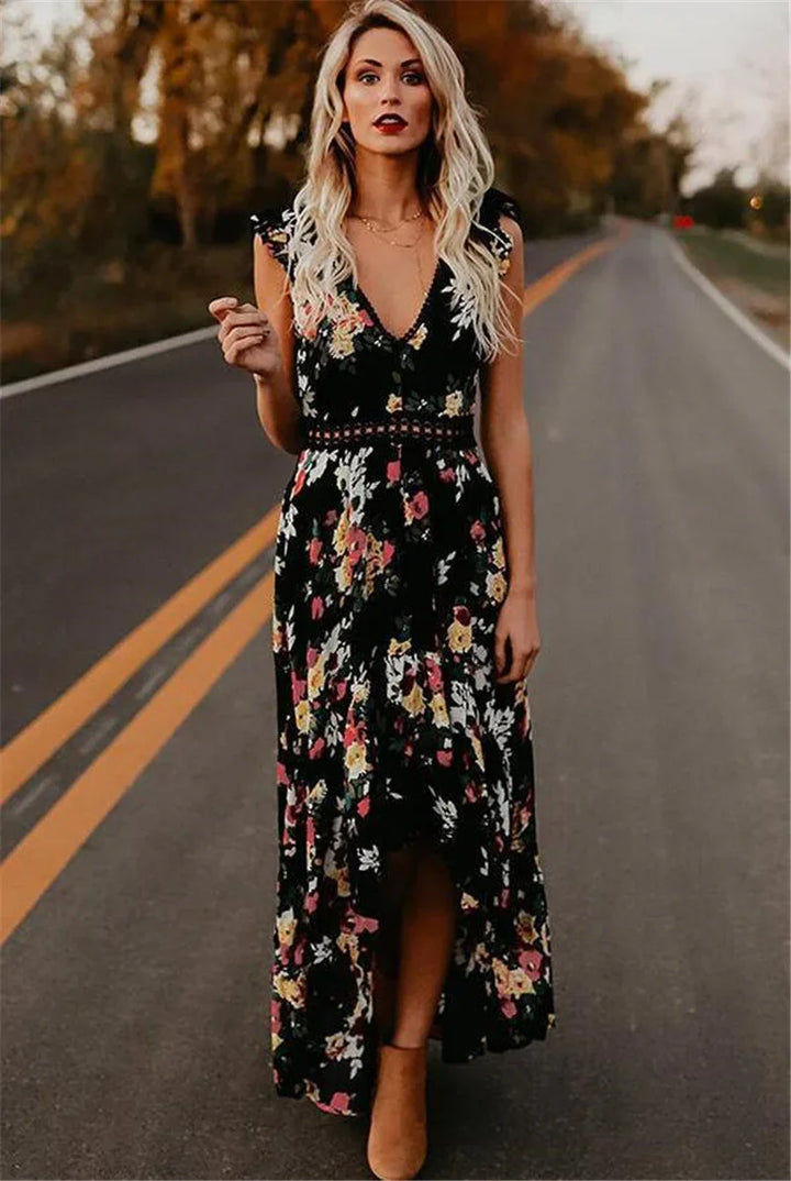 Blonde woman in a black floral maxi dress standing on an empty road with autumn trees