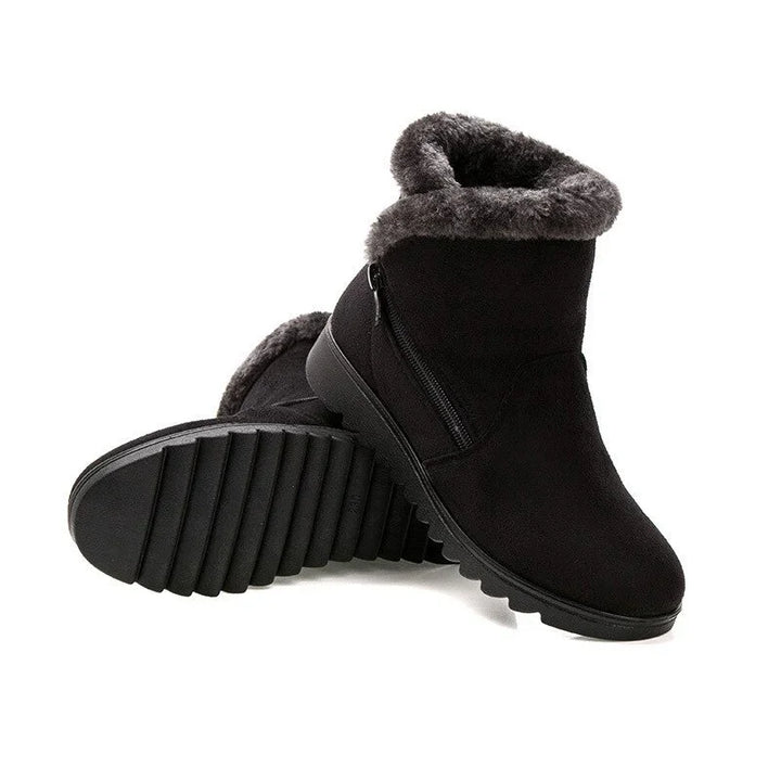 Black winter boots with plush gray fur lining and side zipper on white background