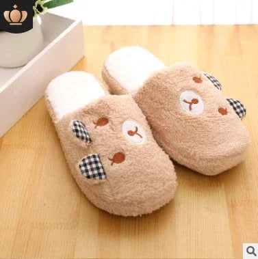 Cozy beige bear-shaped plush slippers with checkered ears on wooden floor