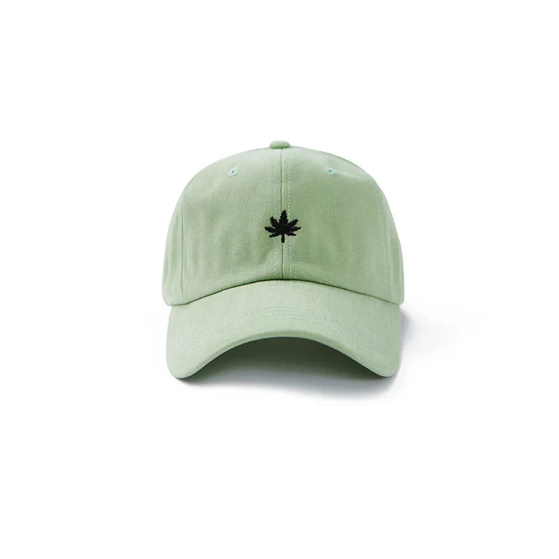Light green baseball cap with black embroidered maple leaf logo on front, isolated on white background