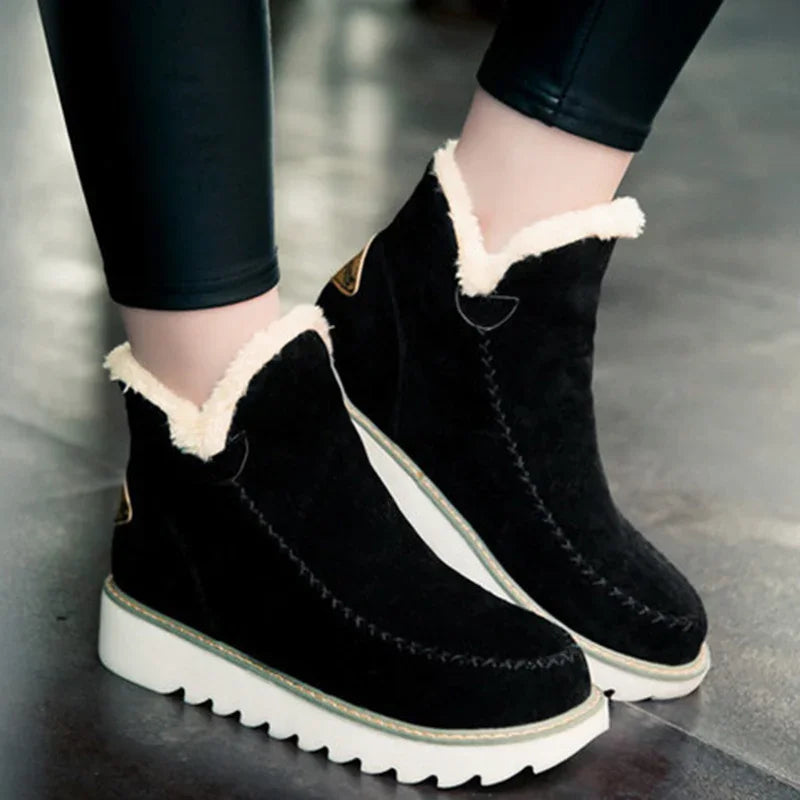 Black suede winter boots with white fur trim and thick white rubber soles worn with black leggings