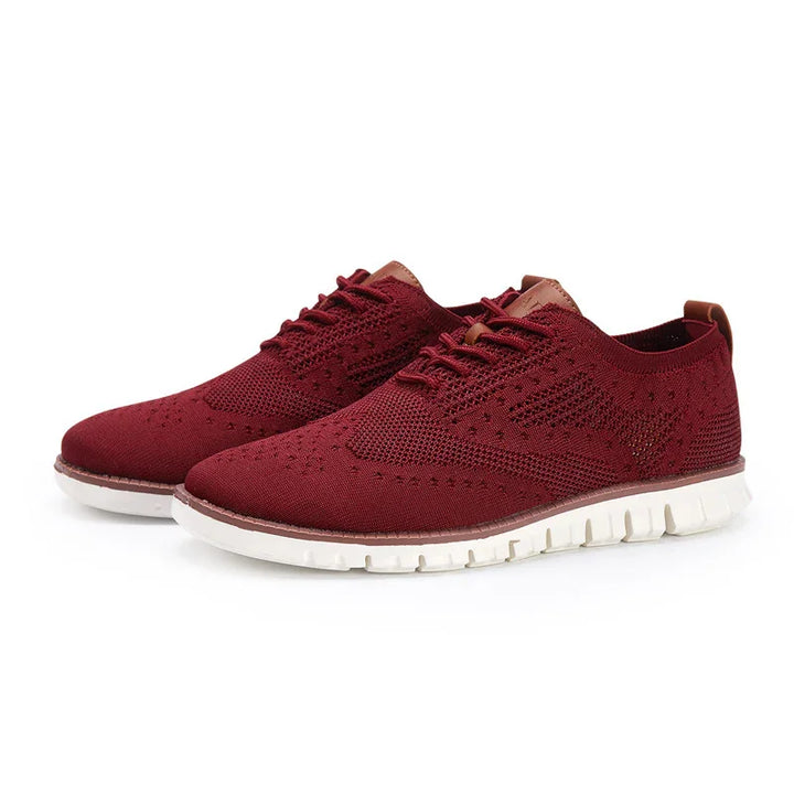 Pair of stylish burgundy knit casual shoes with white flexible soles on white background
