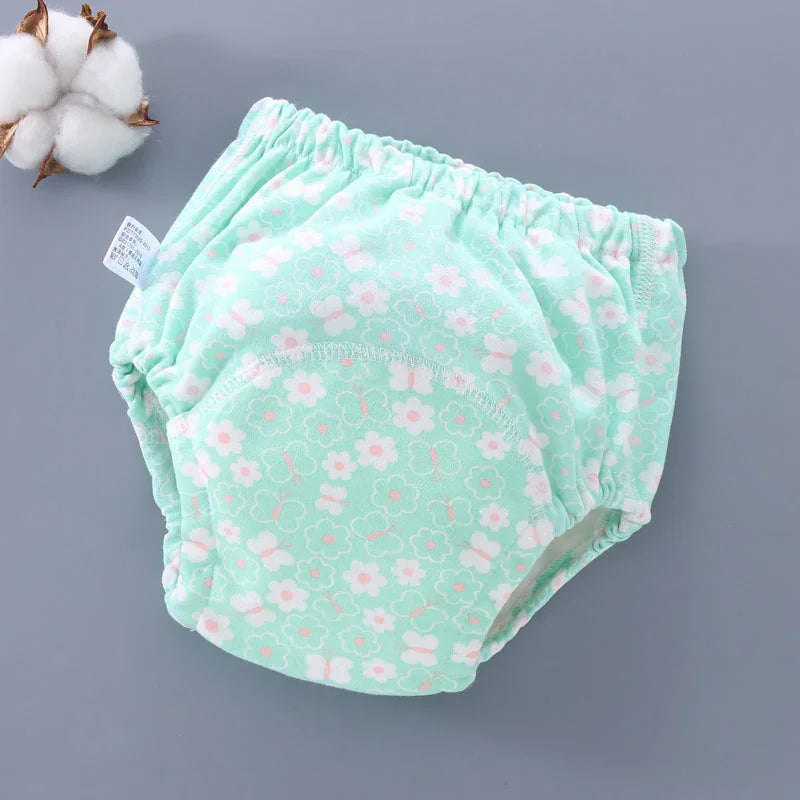Mint green baby training pants with white and pink floral and butterfly print on gray background