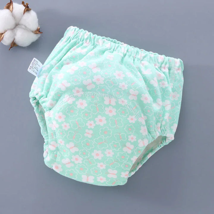 Mint green baby training pants with white and pink floral and butterfly print on gray background