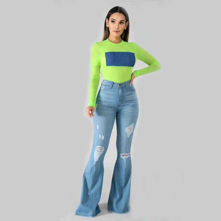 Woman wearing neon green long-sleeve top with blue square and distressed light blue flare jeans