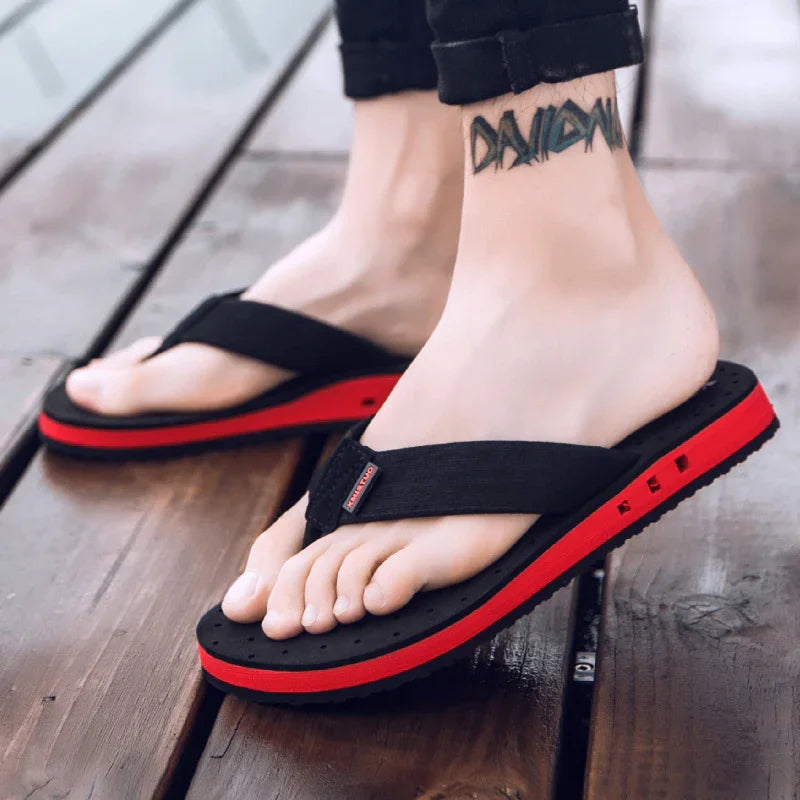 Close-up of feet wearing black and red casual flip flop sandals on wooden floor