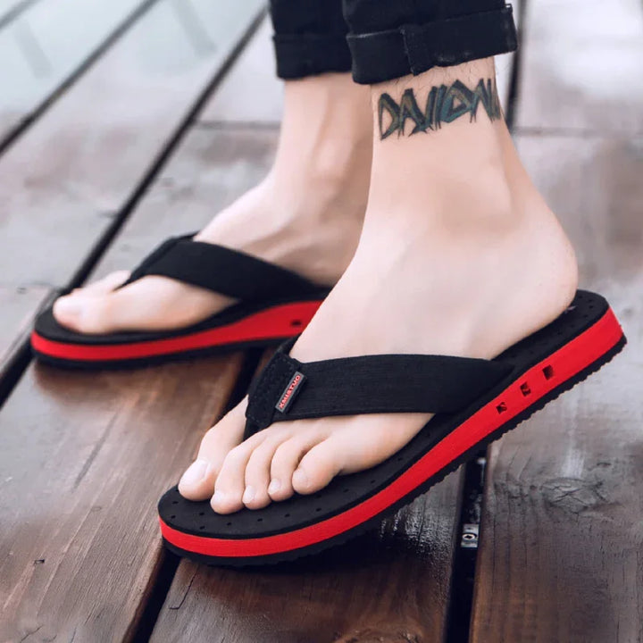 Close-up of feet wearing black and red casual flip flop sandals on wooden floor