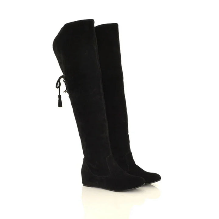 Pair of black over-the-knee suede boots with side tie detail on white background