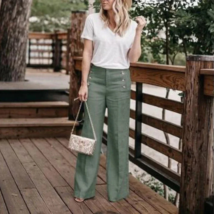 Woman wearing white v-neck t-shirt and high-waisted olive green wide-leg pants on wooden deck