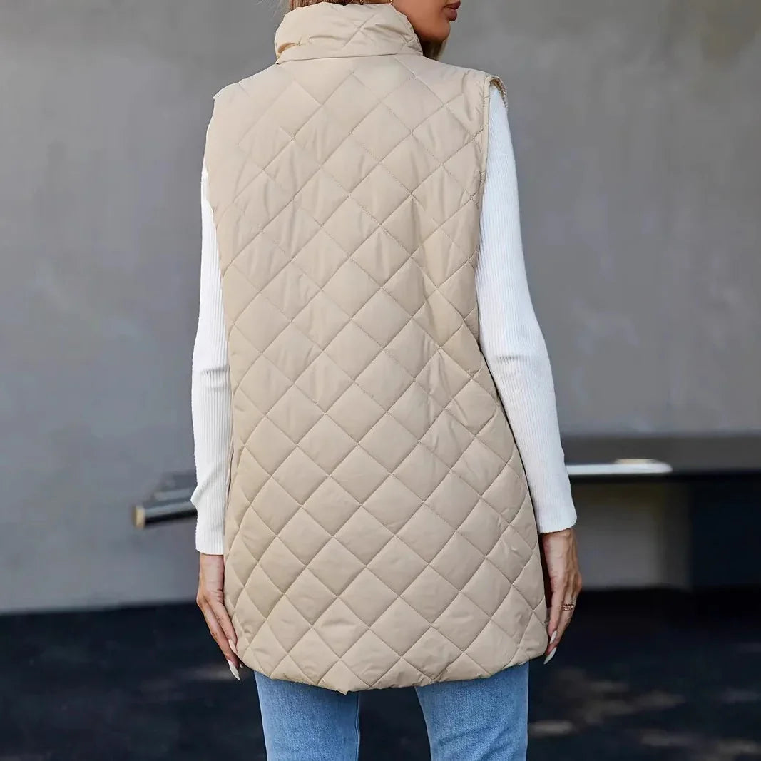Back view of woman wearing beige quilted sleeveless vest over white long sleeve top and blue jeans