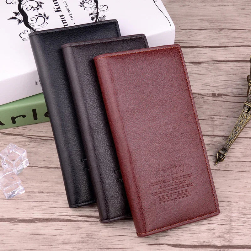Three leather long wallets in brown, dark brown, and black on wooden surface with decorative book and Eiffel Tower model
