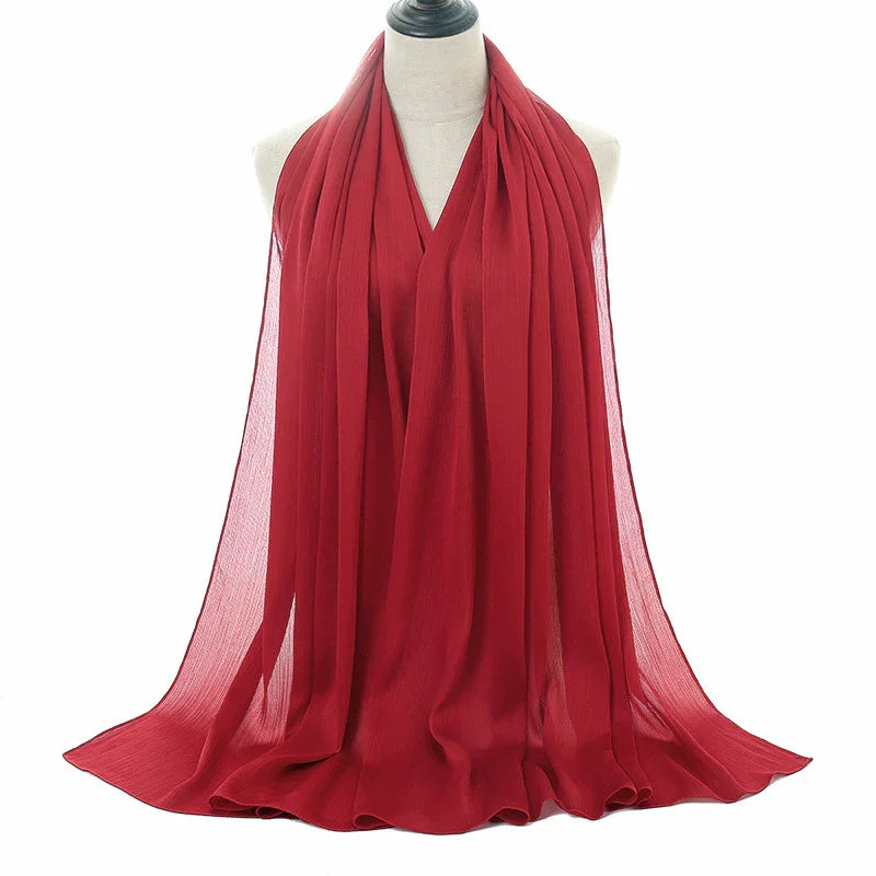 Elegant red chiffon scarf draped on mannequin with soft pleats and flowing fabric