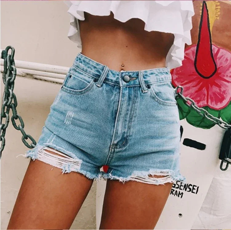 Close-up of woman wearing distressed high-waist denim shorts and white ruffled crop top with belly piercing