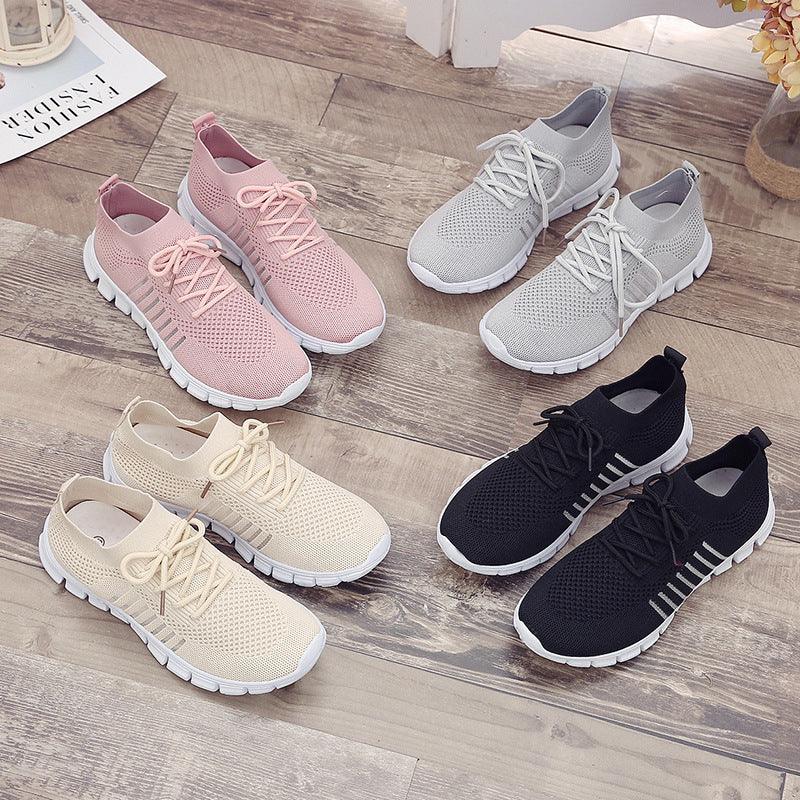 Four pairs of knit breathable sneakers in pink, gray, beige, and black on wooden floor