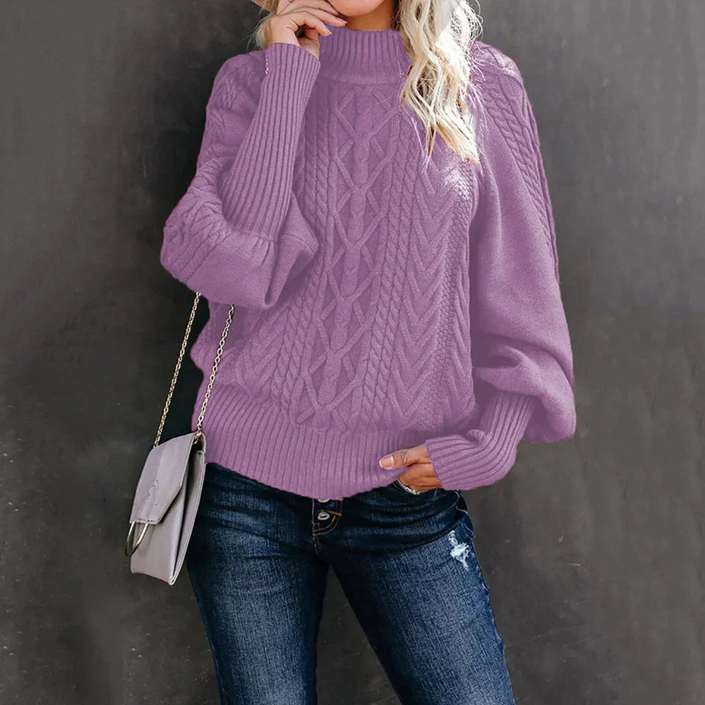 Woman wearing lilac cable knit sweater with puff sleeves and dark ripped jeans, holding gray handbag