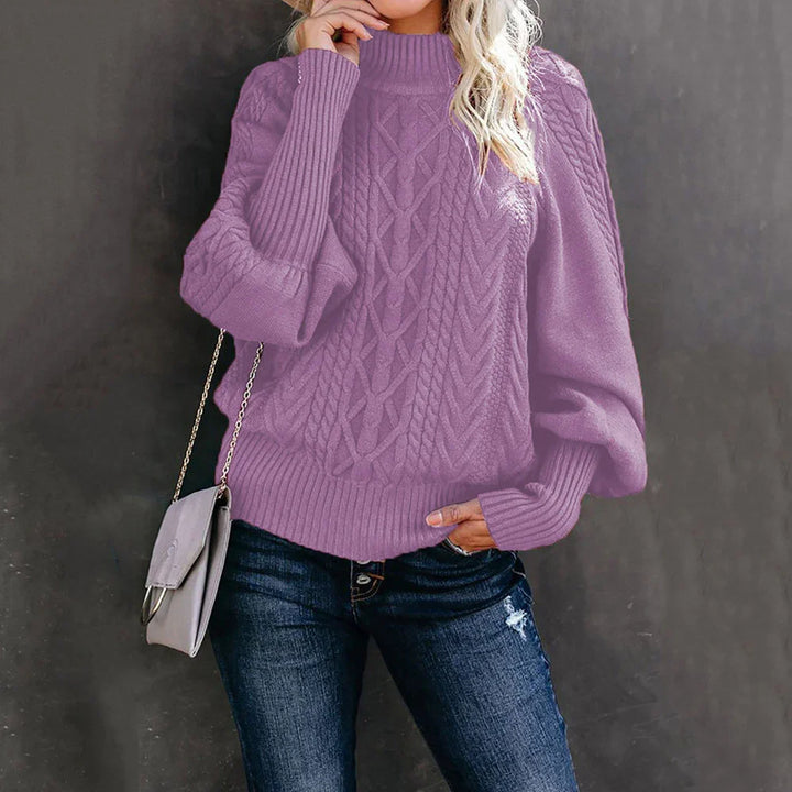 Woman wearing lilac cable knit sweater with puff sleeves and dark ripped jeans, holding gray handbag