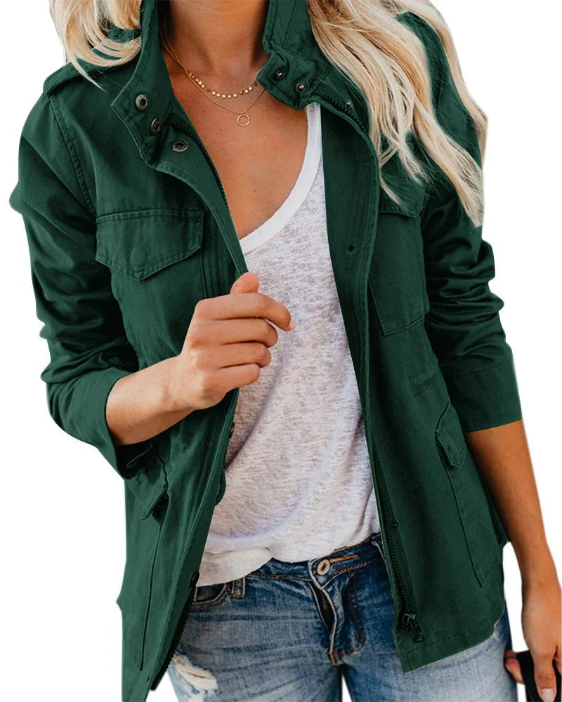 Woman wearing dark green utility jacket over white shirt and distressed blue jeans with layered gold necklaces