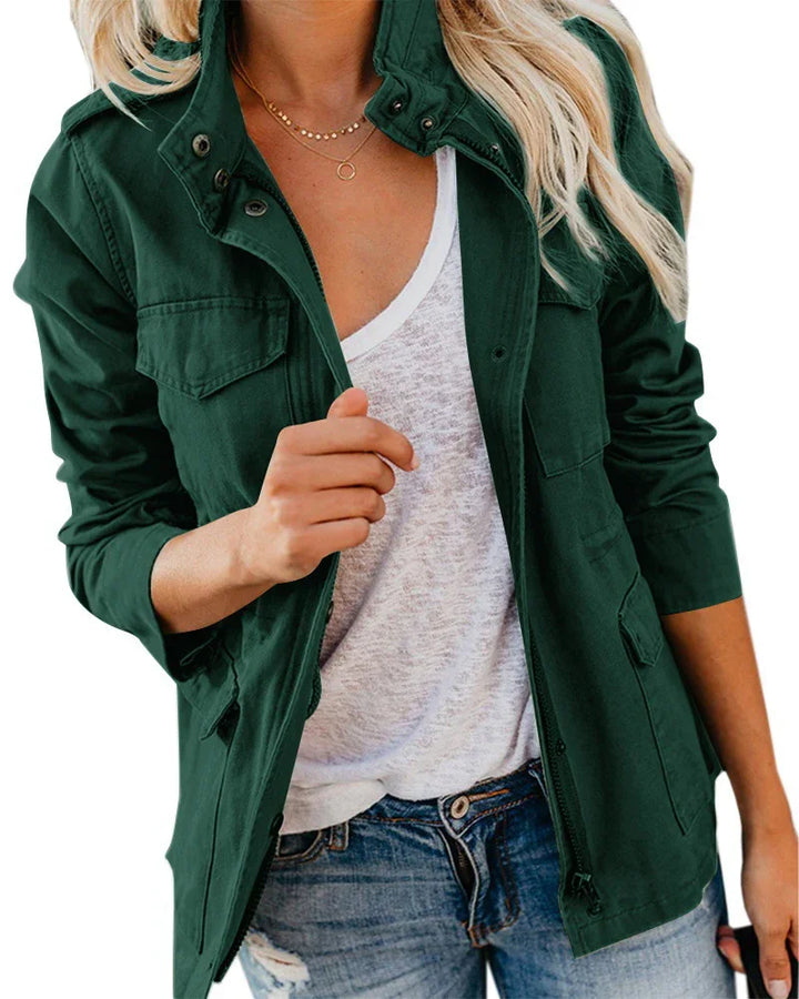 Woman wearing dark green utility jacket over white shirt and distressed blue jeans with layered gold necklaces