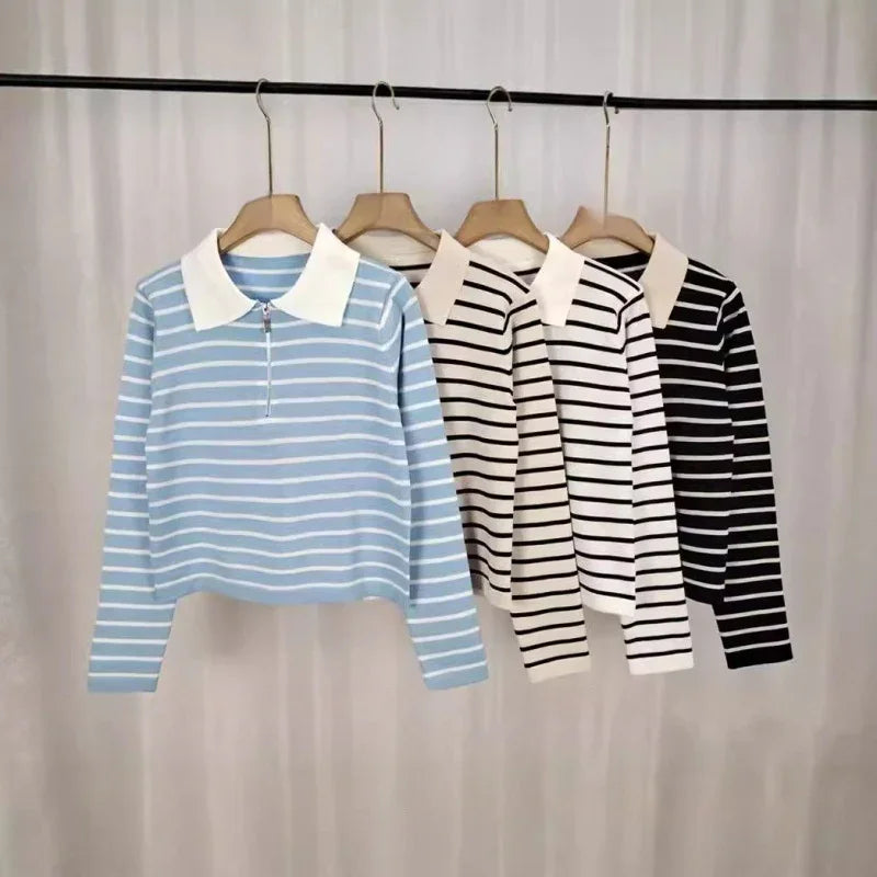 Striped long-sleeve polo shirts in blue, beige, white, and black hanging on wooden hangers