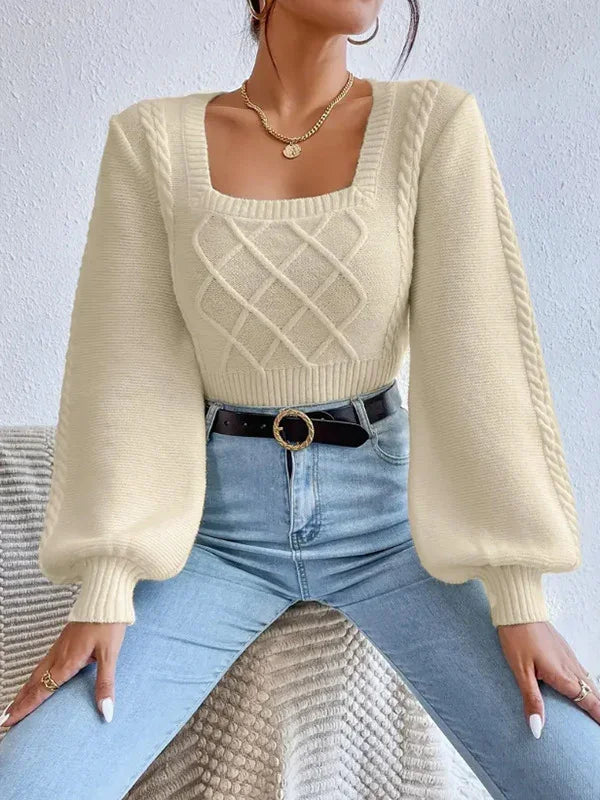Woman wearing cream cable knit sweater with puff sleeves and square neckline, paired with high-waisted blue jeans