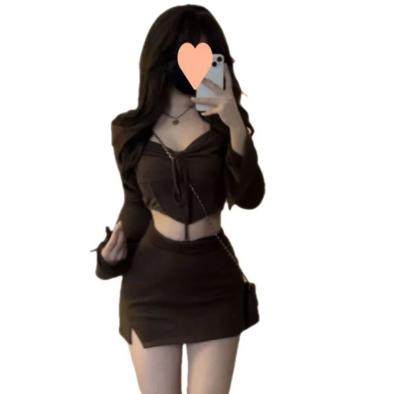 Woman wearing black crop top and mini skirt, holding phone in mirror selfie