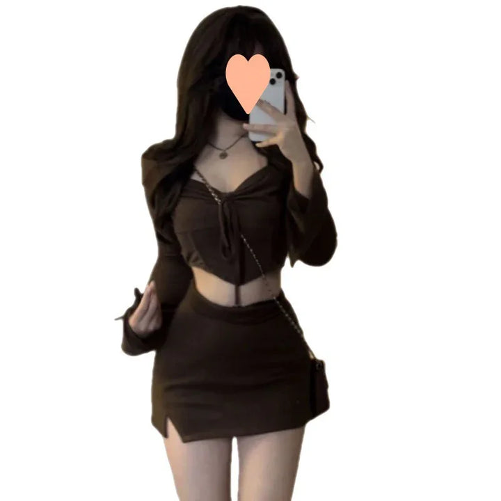 Woman wearing black crop top and mini skirt, holding phone in mirror selfie