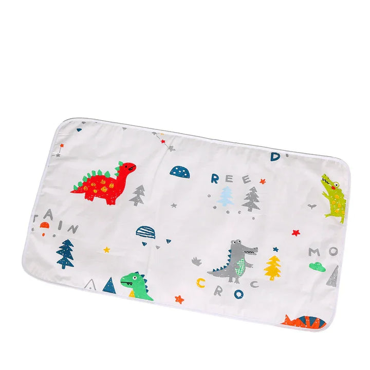 White baby changing pad with colorful dinosaurs, trees, stars, and alphabet letters pattern