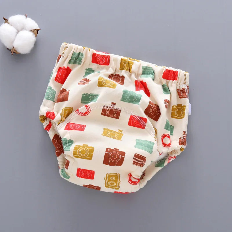 Cream baby diaper cover with colorful vintage camera prints on gray background with cotton flower