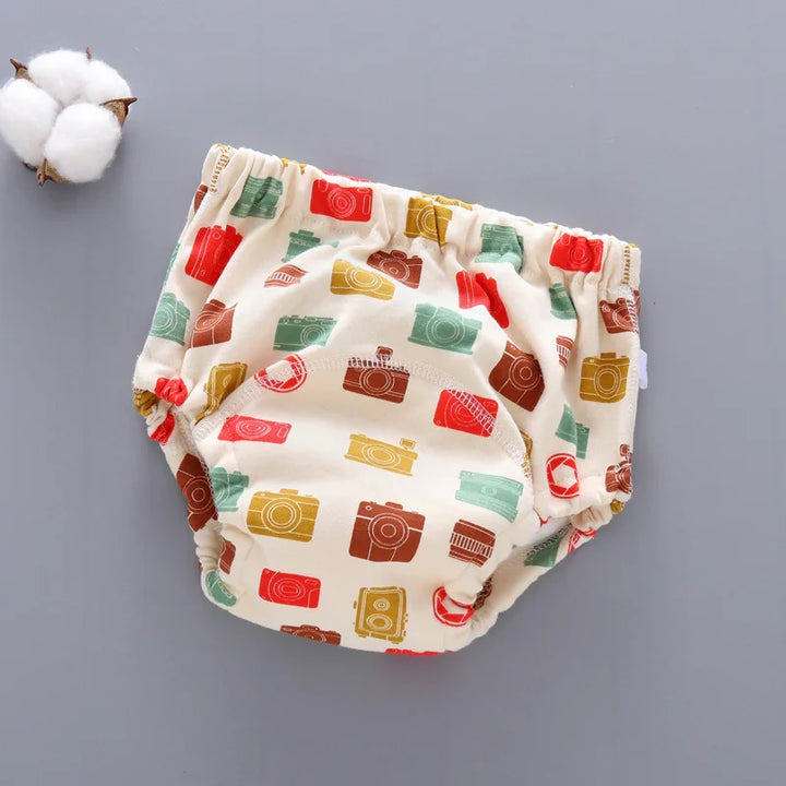 Cream baby diaper cover with colorful vintage camera prints on gray background with cotton flower