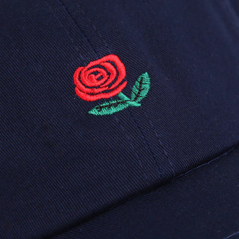 Close-up of navy blue cap with embroidered red rose and green leaves design