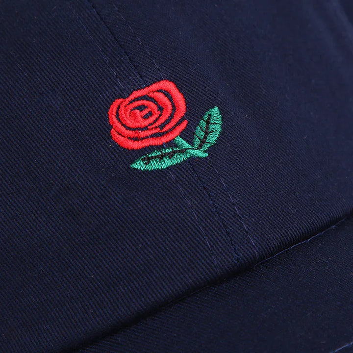 Close-up of navy blue cap with embroidered red rose and green leaves design