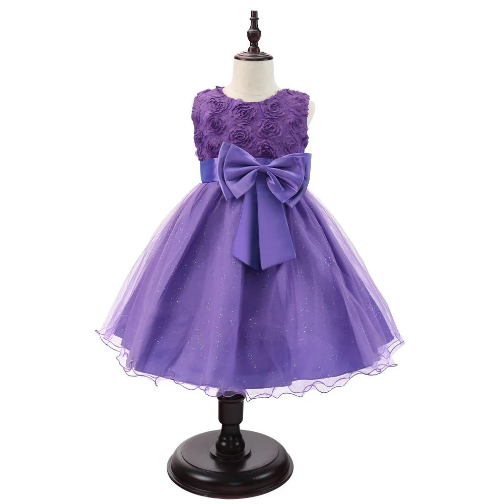 Purple sleeveless girl's party dress with floral bodice, large bow, and glittery tulle skirt on mannequin
