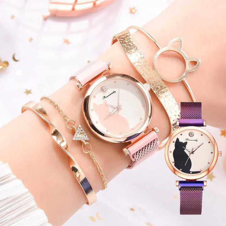 Wrist with two cat-themed watches and gold bracelets on a light background with star patterns
