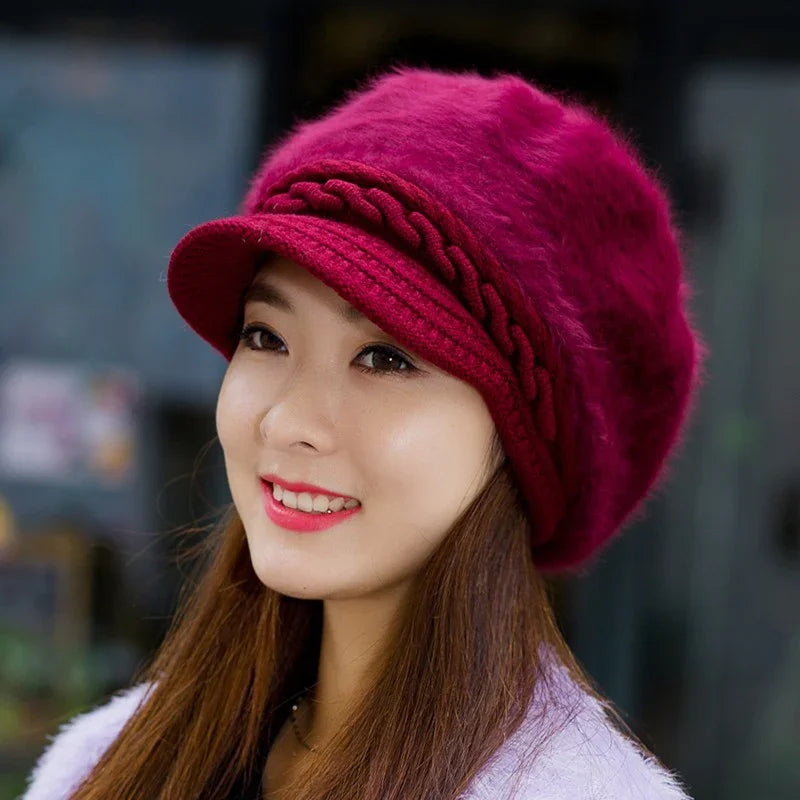 Smiling woman wearing a stylish fuzzy red knit hat with braided detail and pink lipstick