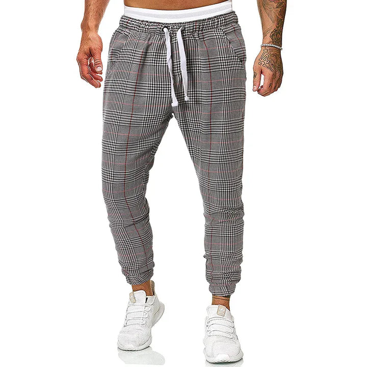 Men's slim fit plaid jogger pants with white drawstring and elastic cuffs, worn with white sneakers