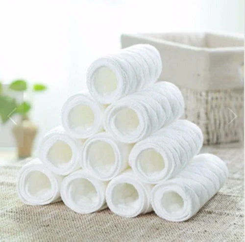 Stack of white rolled towels on textured surface with blurred basket and green plant in background