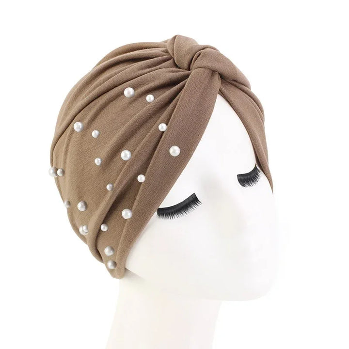 Brown turban headwrap with pearl embellishments on mannequin with long lashes